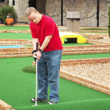  Adult with special needs putts golf ball.